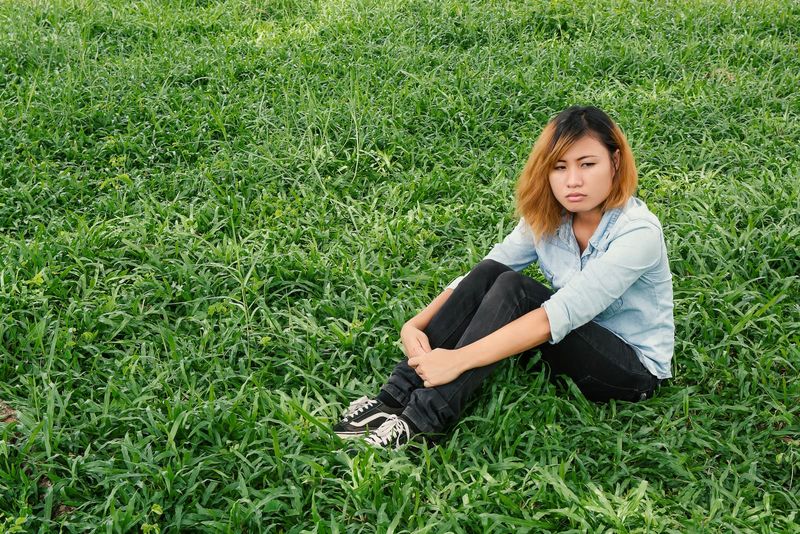 Nachdenkliche Frau sitzt auf dem Gras