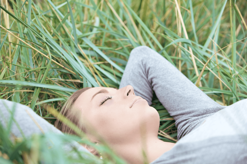 Eine schöne Frau liegt mit geschlossenen Augen im Gras