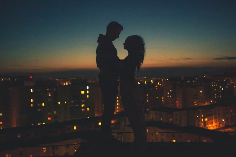 Silhouette von Mann und Frau, die auf dem Dachgebäude stehen