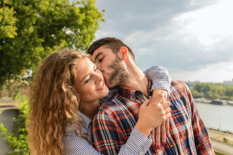 Mann im karierten Hemd küsst Frau im Freien