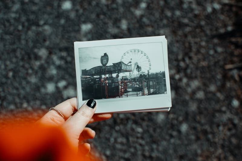 Frau, die Polaroidbild eines amüsanten Parks beschnitten hält