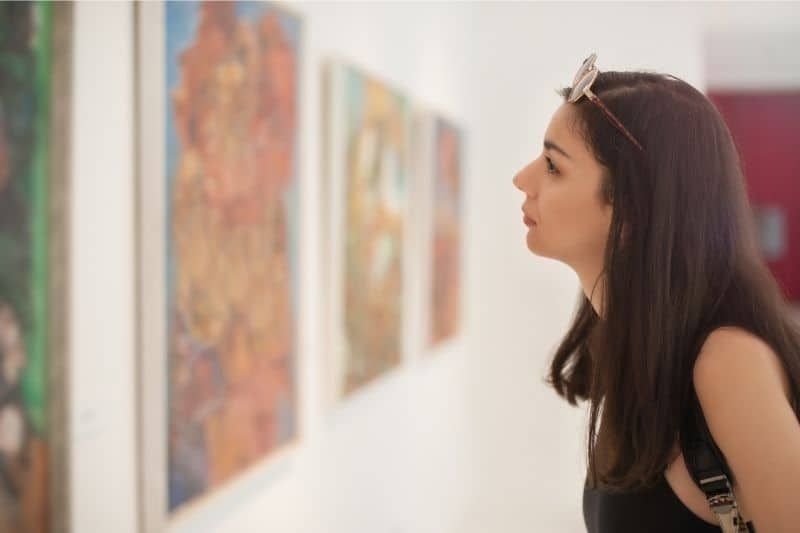 Frau, die die Kunst an der Wand in einer Kunstgalerie betrachtet