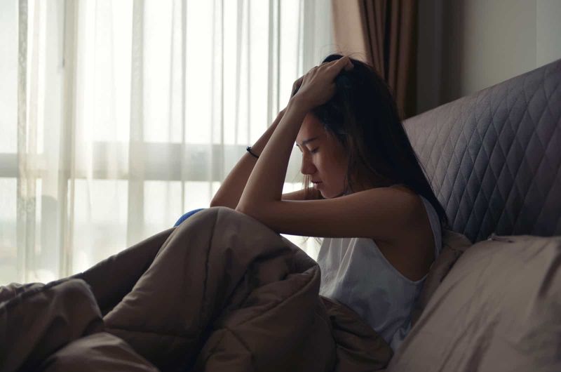 Junge Frau weint in ihrem Bett, weil die Menschen sich nur um sich selbst kümmern