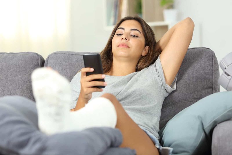 junge Frau, die auf der Couch eine SMS schreibt