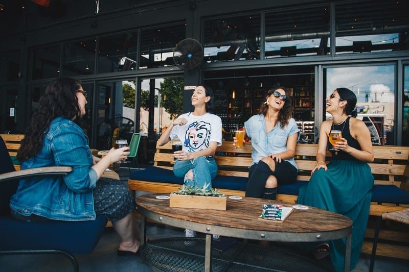 Vier Frauen unterhalten sich und lachen vor einem Café