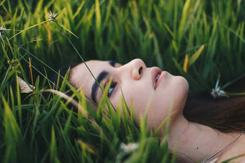 traurige Frau, die im Gras liegt