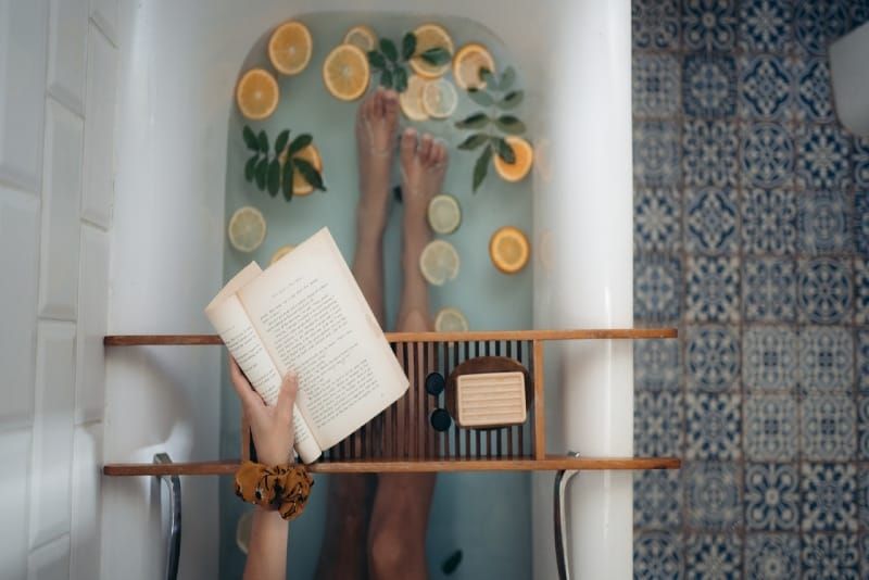 Frau hält Buch, während sie in der Badewanne sitzt