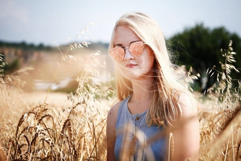 blonde Frau mit Sonnenbrille im Weizenfeld