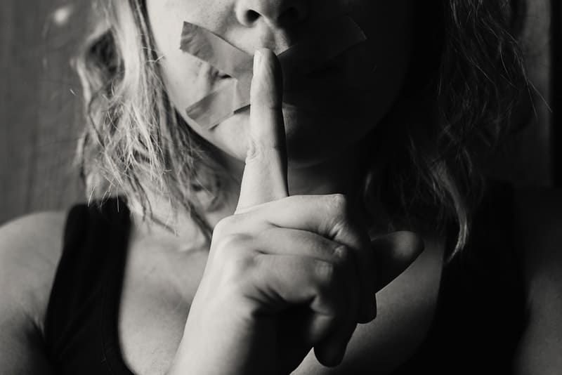 Frau mit verschlossenen Lippen und mit Klebeband signiertes Schweigen in Schwarz und Weiß