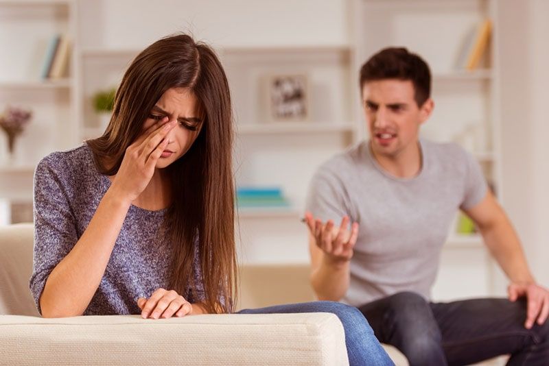 Mann schreit eine weinende Frau im Wohnzimmer an