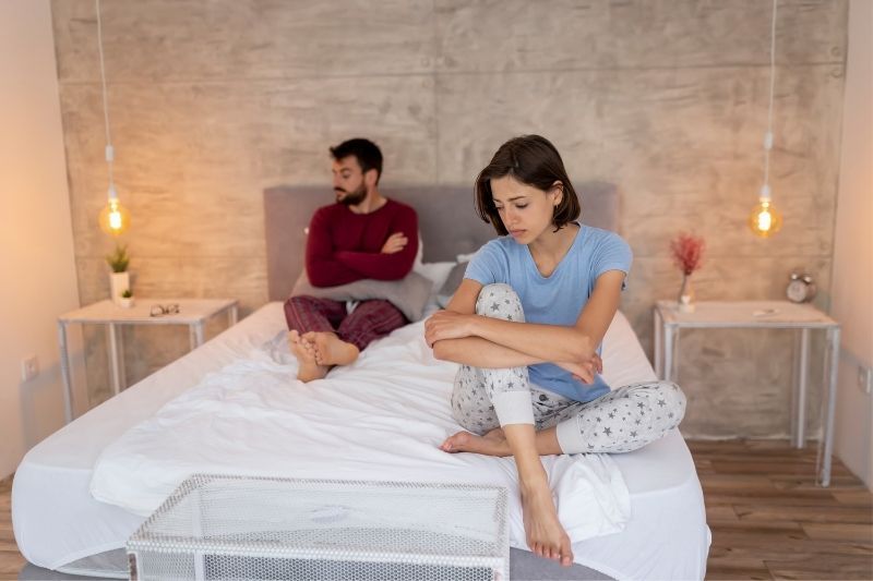 Unzufriedenes Paar, das Probleme mit der Ehe hat und auf dem Bett sitzt