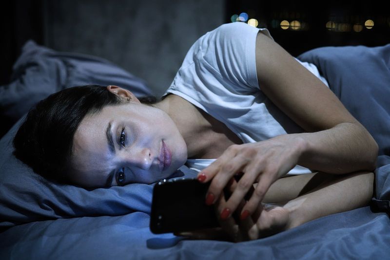 traurige Frau im Bett, die SMS schreibt