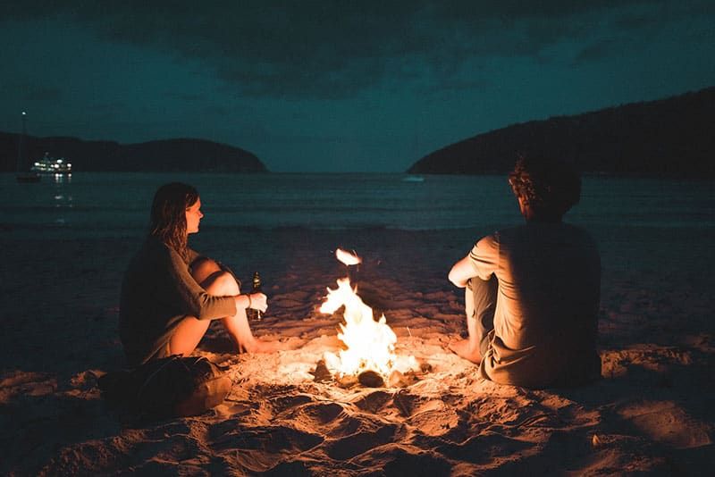 Paar sitzt am Feuer am Strand