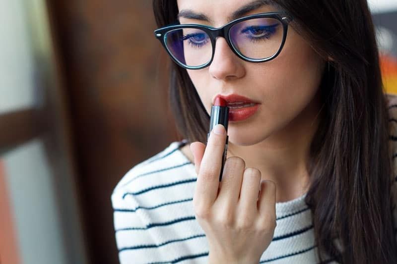 Frau mit Brille schminkt sich