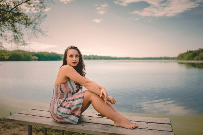 Frau sitzt auf einer Bank vor einem See