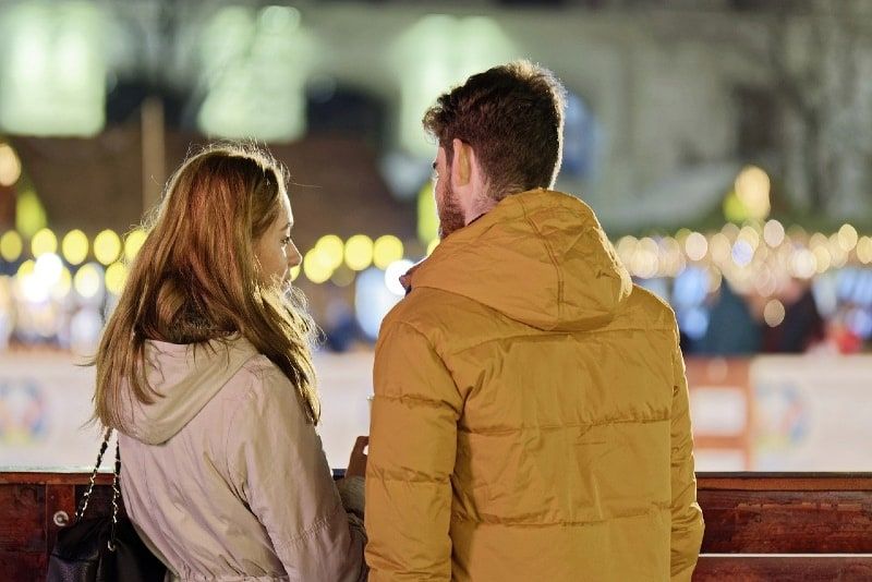 Mann in gelber Jacke und Frau stehen draußen und reden