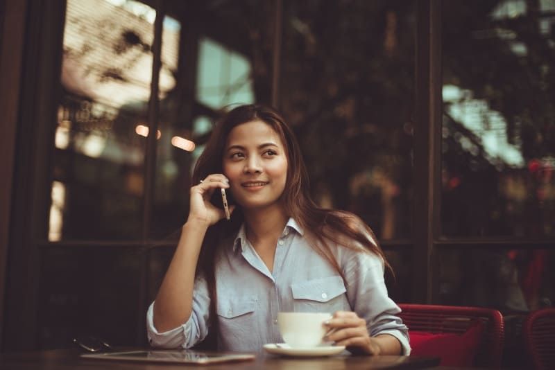 Frau telefoniert, während sie im Café sitzt