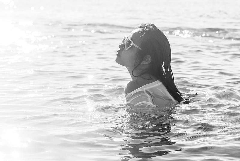 Frau trägt Sonnenbrille beim Schwimmen