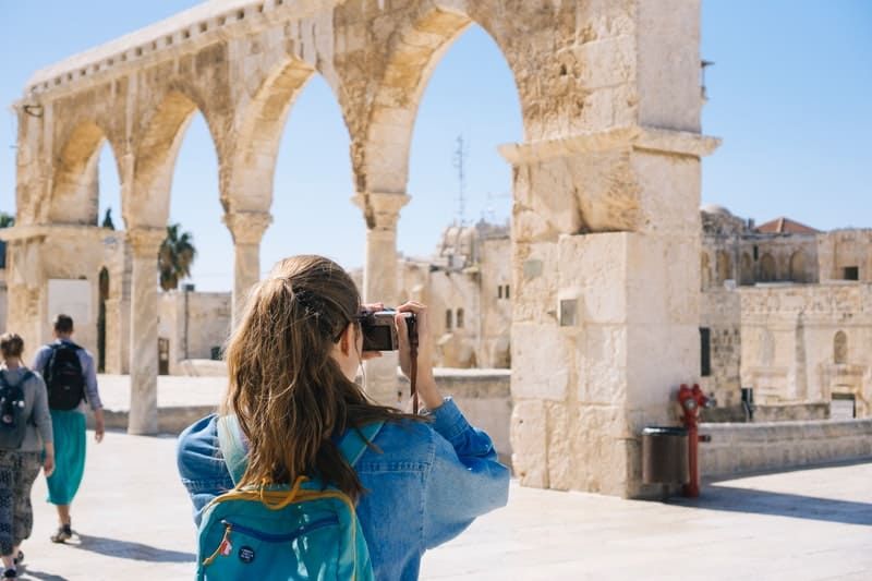 Frau fotografiert die alten Ruinen, während sie mit vielen weiteren Reisenden unterwegs ist