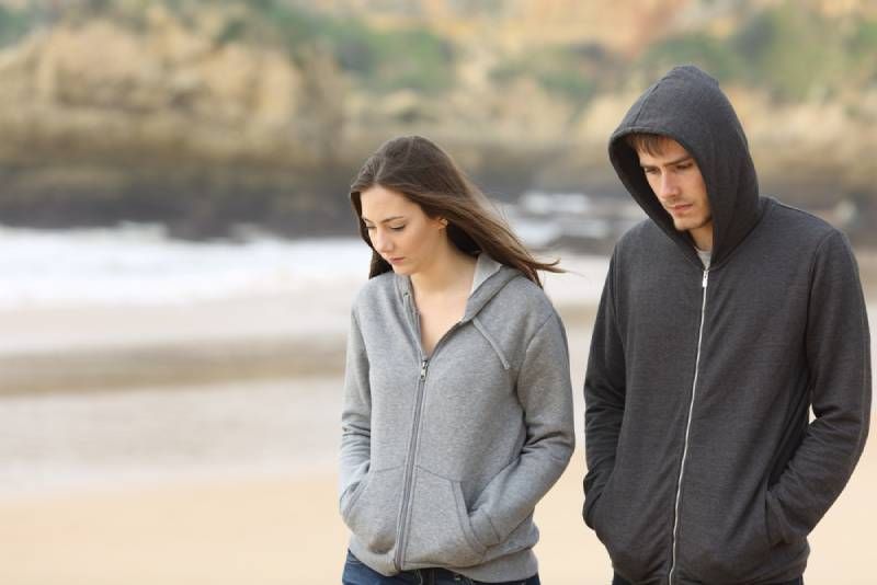 Unglückliches Paar, das am Strand spaziert
