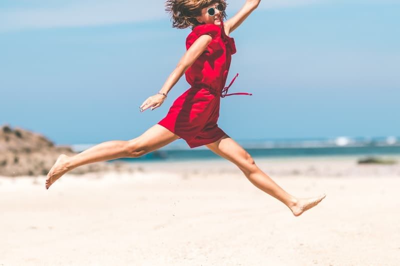 Frau in Rot springt vor Glück in die Küste