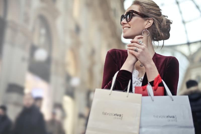 Lächelnde Frau mit Sonnenbrille und Einkaufstüten
