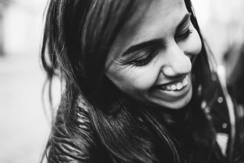Schwarz-Weiß-Porträt eines glücklichen jungen Mädchens mit schönen Haaren