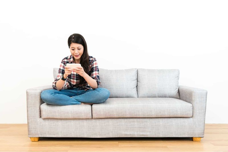 Frau sitzt auf einem grauen Sofa