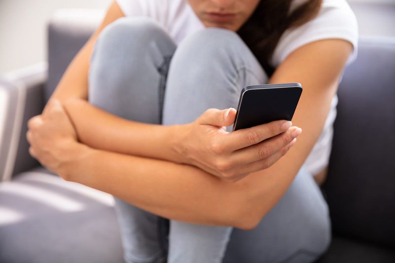 Junge Frau sitzt auf dem Sofa und benutzt Smartphone