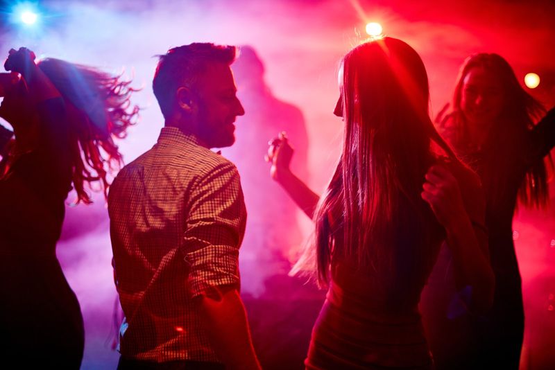 Glückliches Paar und ihre Freunde tanzen im Disco-Club