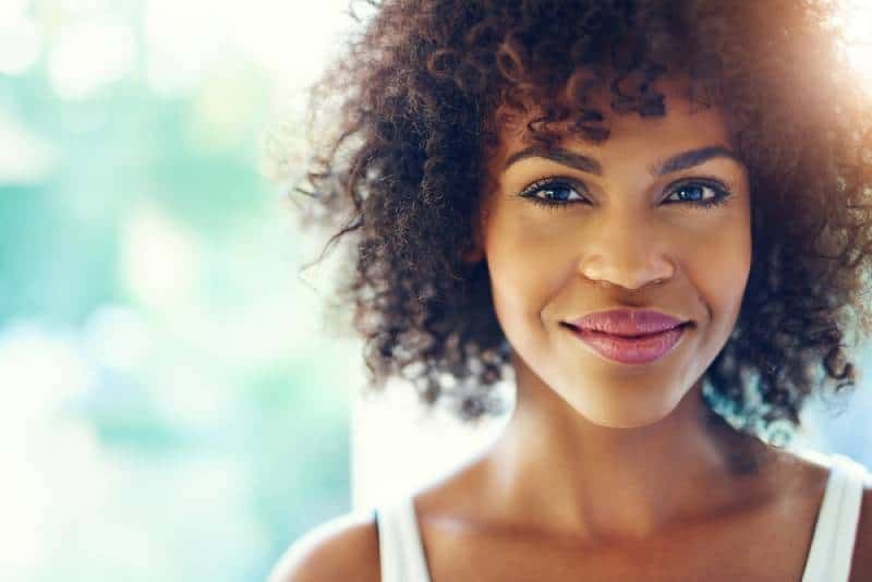 Porträt einer lächelnden jungen schwarzen Frau mit Sonnenlichtfackel