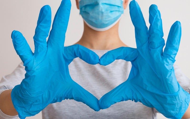 Herzform mit Krankenschwesterhänden, die mit blauen OP-Handschuhen bedeckt sind