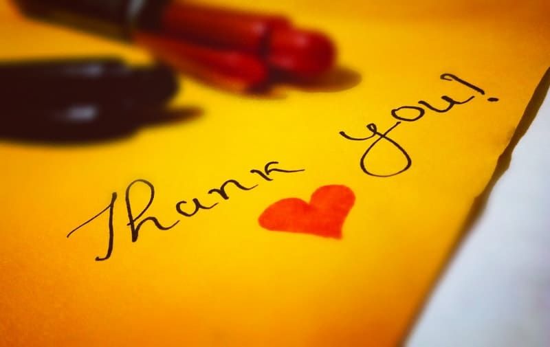 „Dankeschön“-Herztext, geschrieben in gelbem Papier, mit Kugelschreiber über dem Papier platzieren
