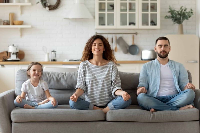 Familie meditiert gemeinsam auf der Couch