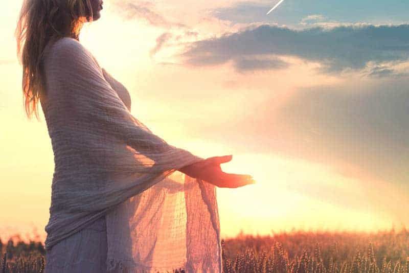Seitenansicht einer Frau, die bei Sonnenuntergang auf dem Feld steht