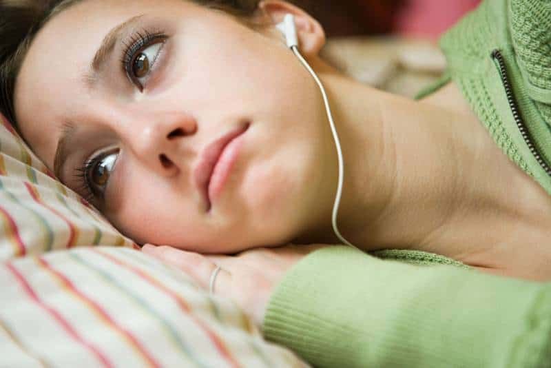 Nahaufnahmefoto einer Frau, die traurige Musik mit Kopfhörern hört