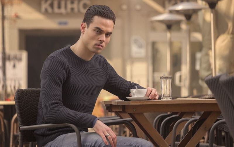 Junger wütender Mann, der draußen in einem Café Kaffee trinkt