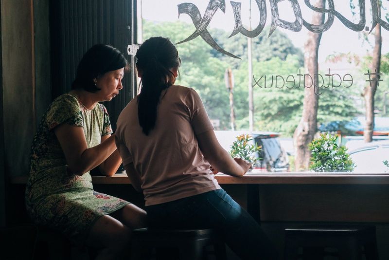 Zwei Frauen sitzen auf schwarzen Holzhockern im Café