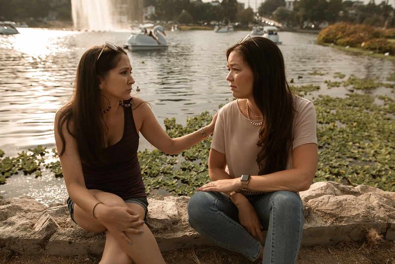 Zwei Freundinnen unterhalten sich, während sie am See sitzen