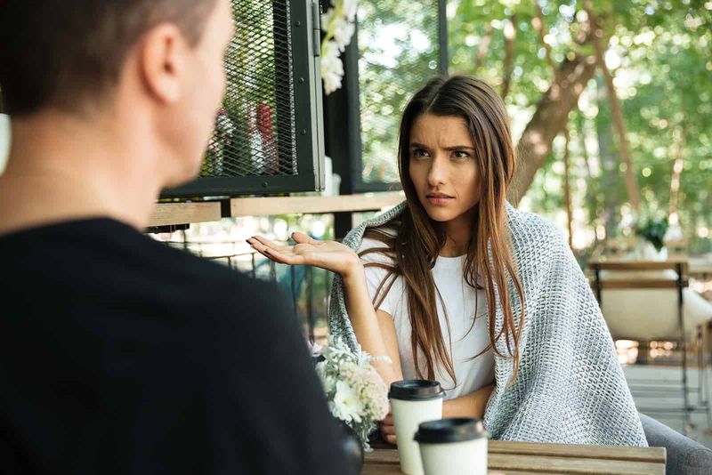verwirrte Frau im Gespräch mit Mann in einem Café