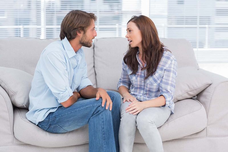 Freundliche Frau, die mit einem Mann spricht, während sie dicht beieinander auf der Couch sitzt