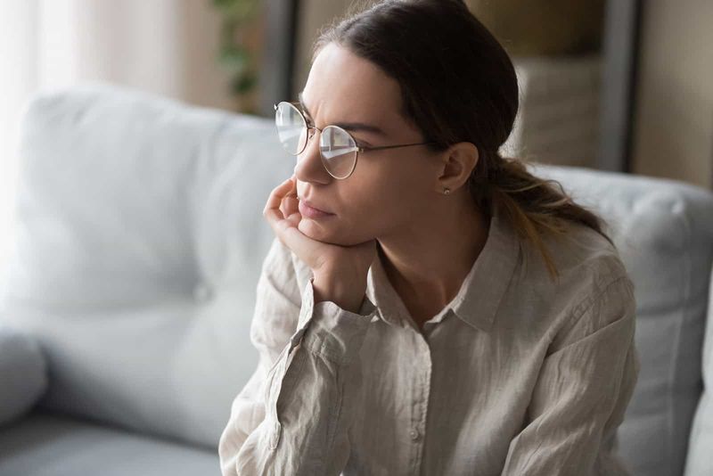 Ernsthafte Frau mit Brille sitzt in tiefen Gedanken