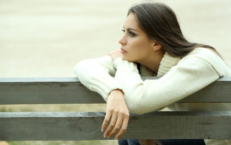Einsame junge Frau sitzt auf einer Bank
