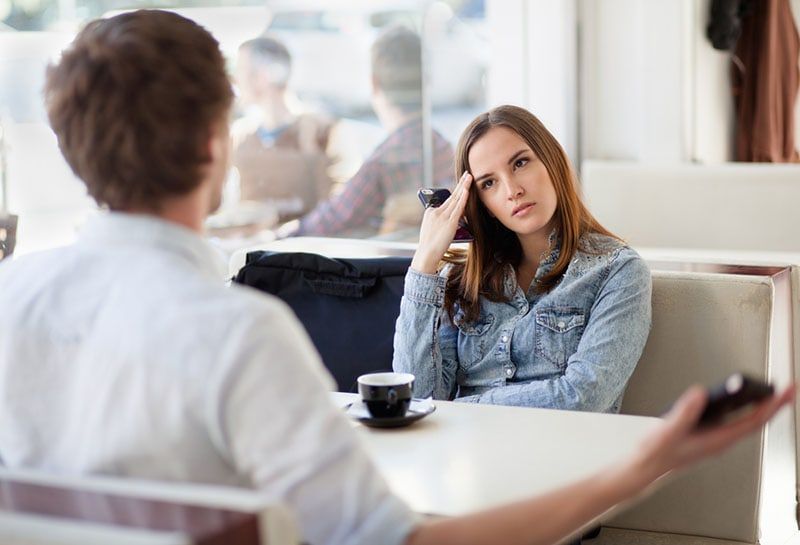ernsthafte Frau hört Mann im Café zu