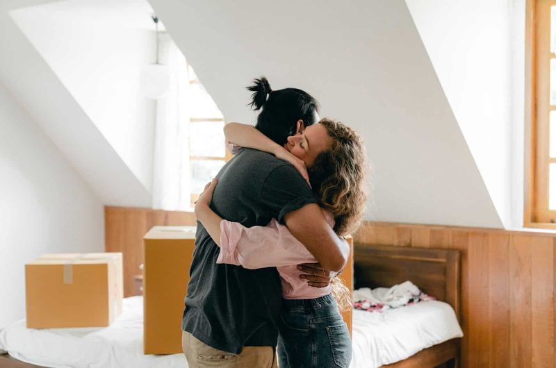 Ehemann und Ehefrau umarmen sich im Schlafzimmer, während sie lächeln und über die Scheidung nachdenken