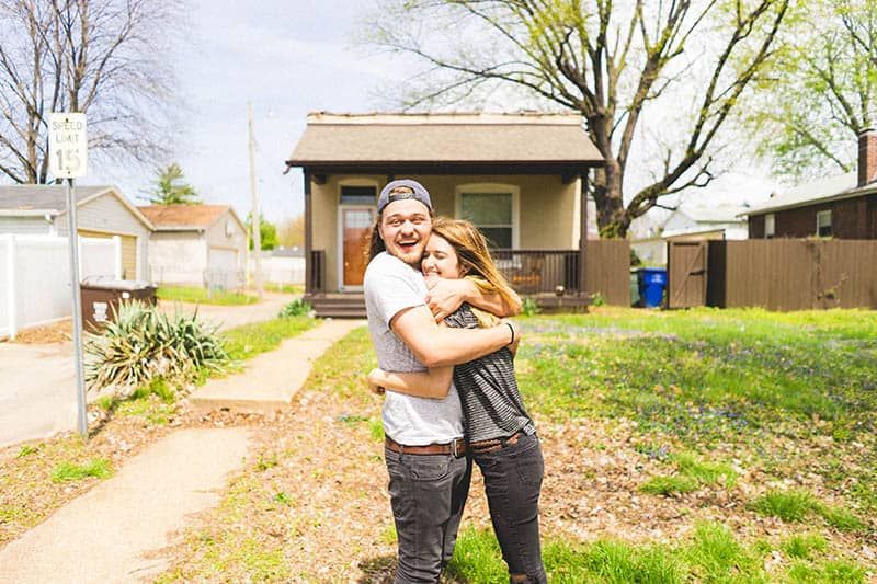 Glückliches Paar, das sich vor einem Haus umarmt