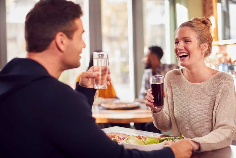 Lächelndes Paar beim Date, das gemeinsam Pizza im Restaurant genießt