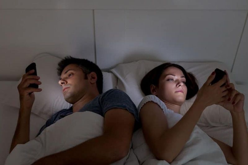 Paar spricht nicht und benutzt ihre Mobiltelefone im Bett