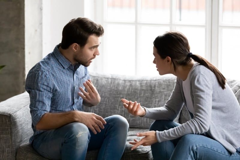 Mann und Frau streiten sich, während sie auf der Couch sitzen