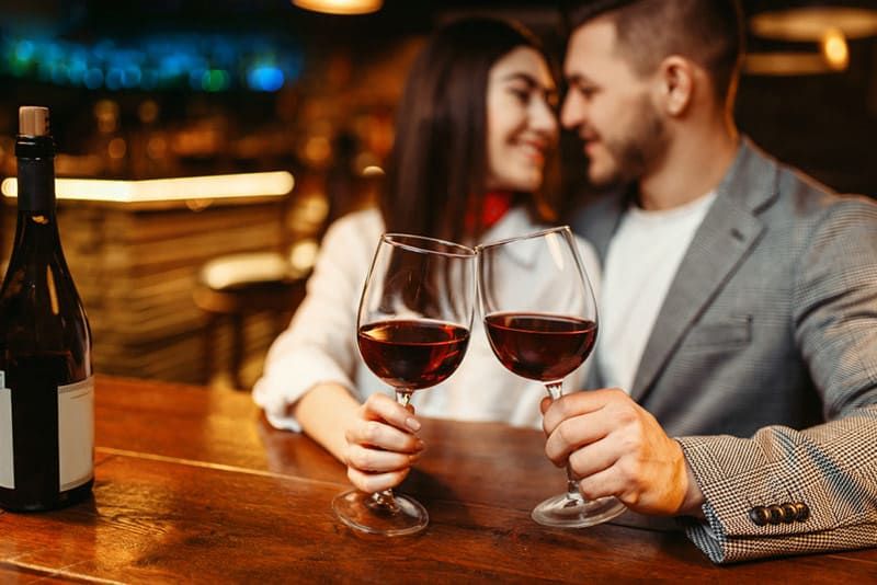 Paar am Date-Abend trinkt aus Weingläsern